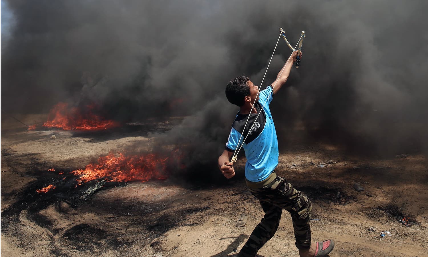 A Palestinian man uses a slingshot during clashes with Israeli forces along the border with the Gaza strip east of Khan Yunis. — AFP