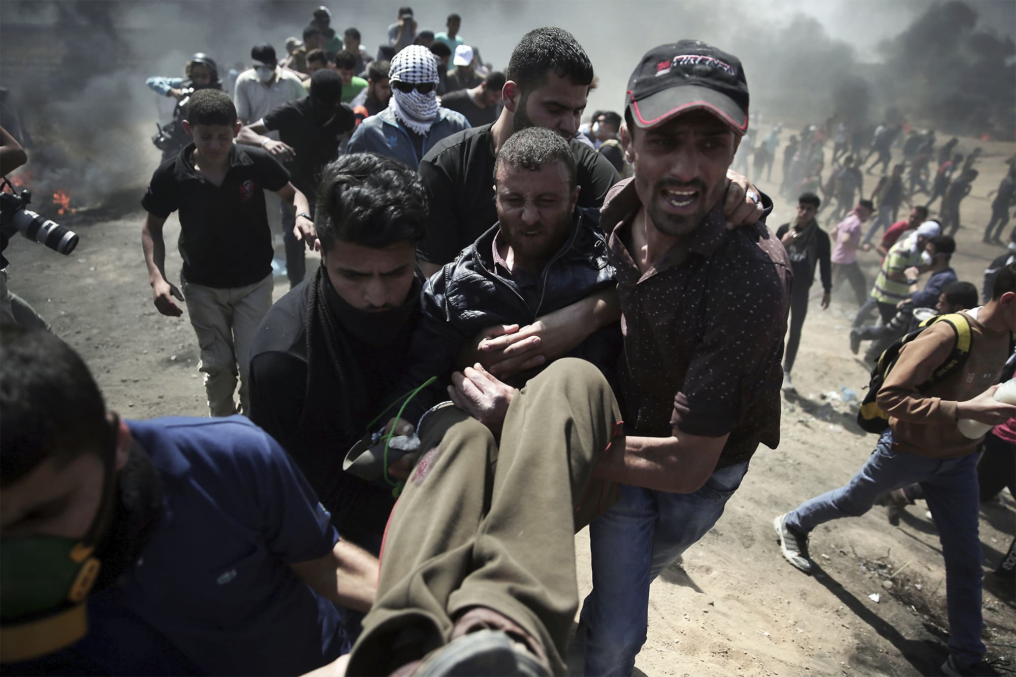 Palestinian protesters carry an injured man who was shot by Israeli troops during a protest at the Gaza Strip's border with Israel. ─ AP