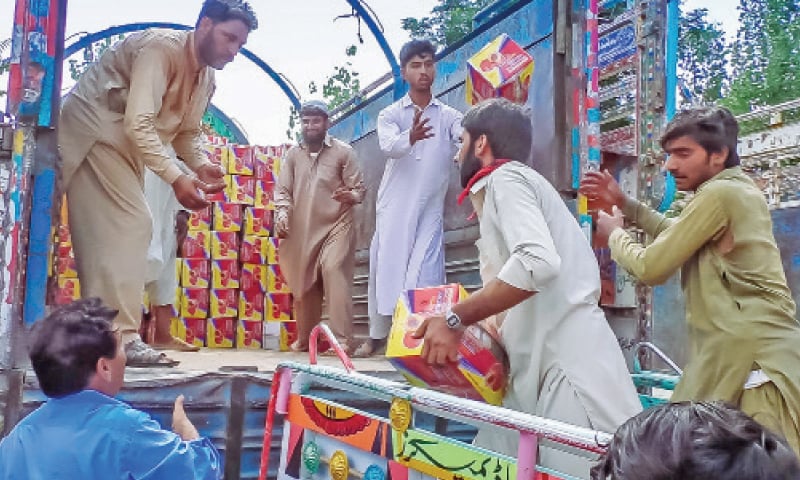 Workers in Swat load peach boxes in a truck for transportation to fruit markets in the country. &mdash; Dawn photo