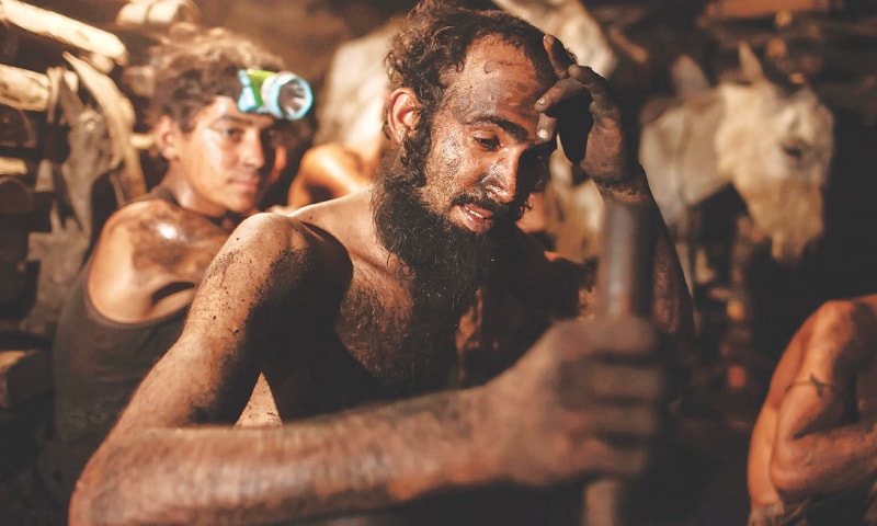 A coal miner wipes sweat off his forehead | Sarah Rashid / Reuters