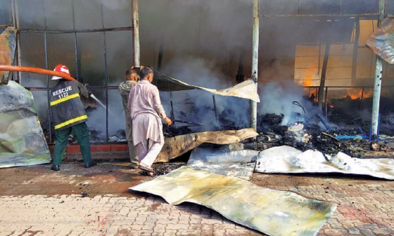 KASUR: A Rescue 1122 official trying his utmost to extinguish fire at Model Bazaar. — Dawn KASUR: A Rescue 1122 official trying his utmost to extinguish fire at Model Bazaar. — Dawn