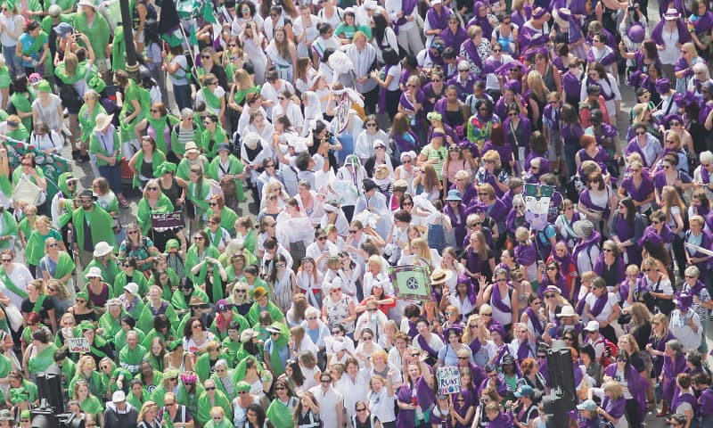LONDON: Women walk together dressed in the suffragette colours of green, white and violet to celebrate a hundred years since women won the right to vote on Sunday.&mdash;AFP