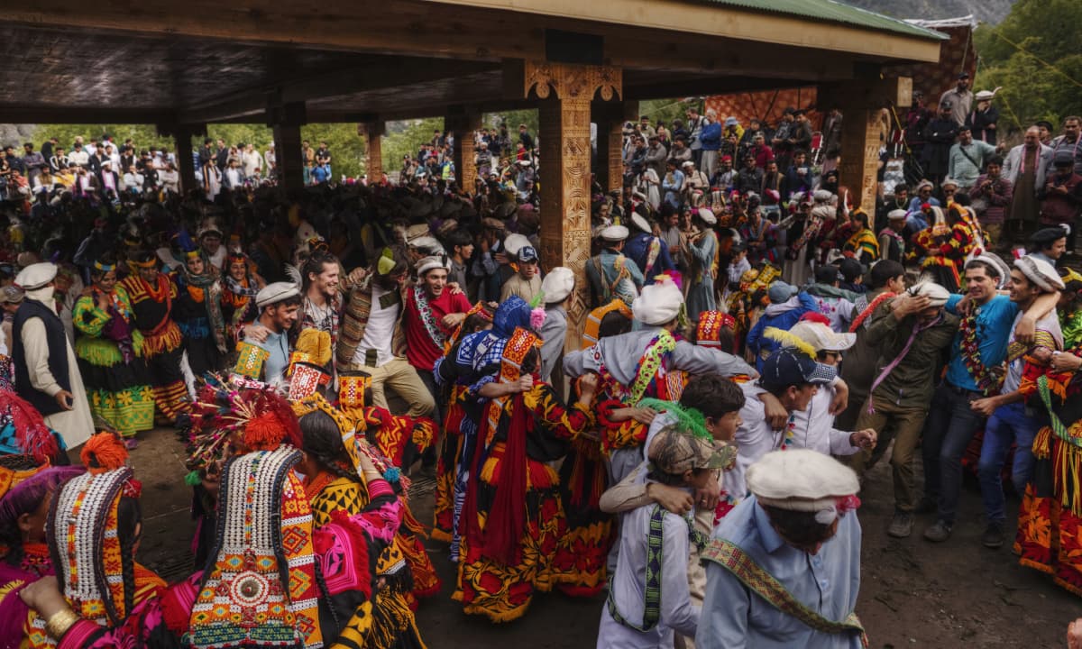 People dance, arm in arm, as spectators watch