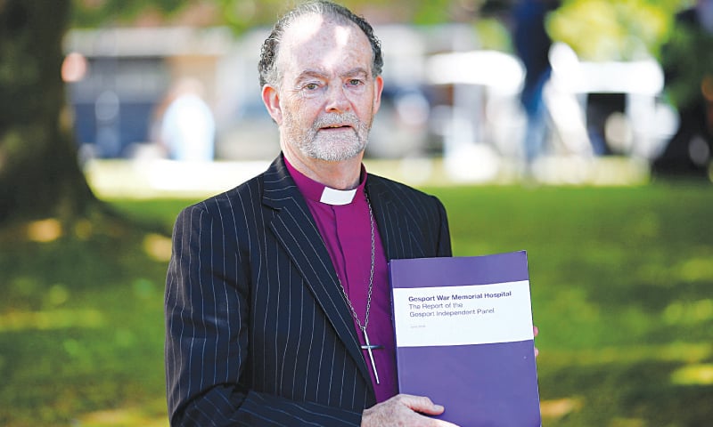PORTSMOUTH (Britain): Bishop James Jones, who led the Gosport War Memorial Hospital inquiry panel, holds a copy of &lsquo;The Report of the Gosport Independent Panel&rsquo;, outside the Portsmouth Cathedral on Wednesday.&mdash;Reuters