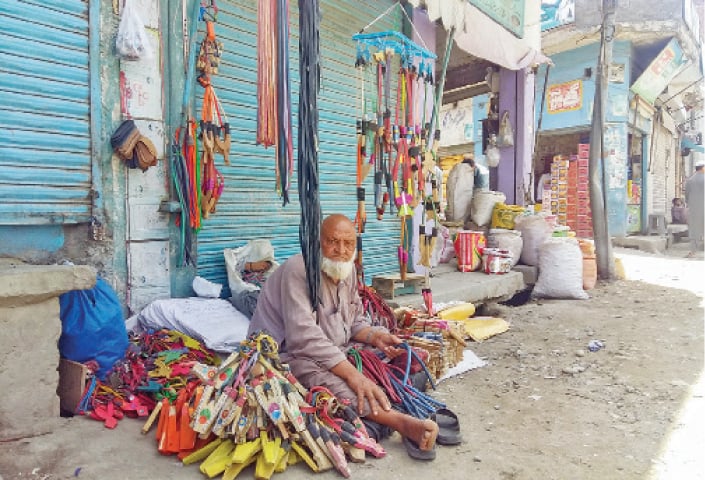 Juma Khan waits for customers in Mingora Bazaar. — Dawn