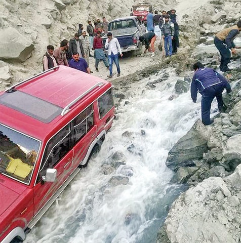 A tourists’ vehicle stranded in a stream on Naltar Road, Gilgit. — Dawn