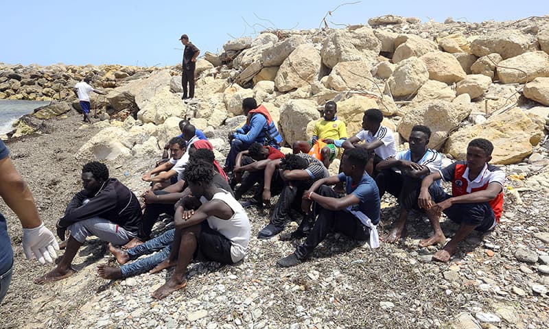 Migrants who survived the sinking of an inflatable dinghy boat off of the coast of Libya are grouped on the shore of al-Hmidiya. &mdash; AFP