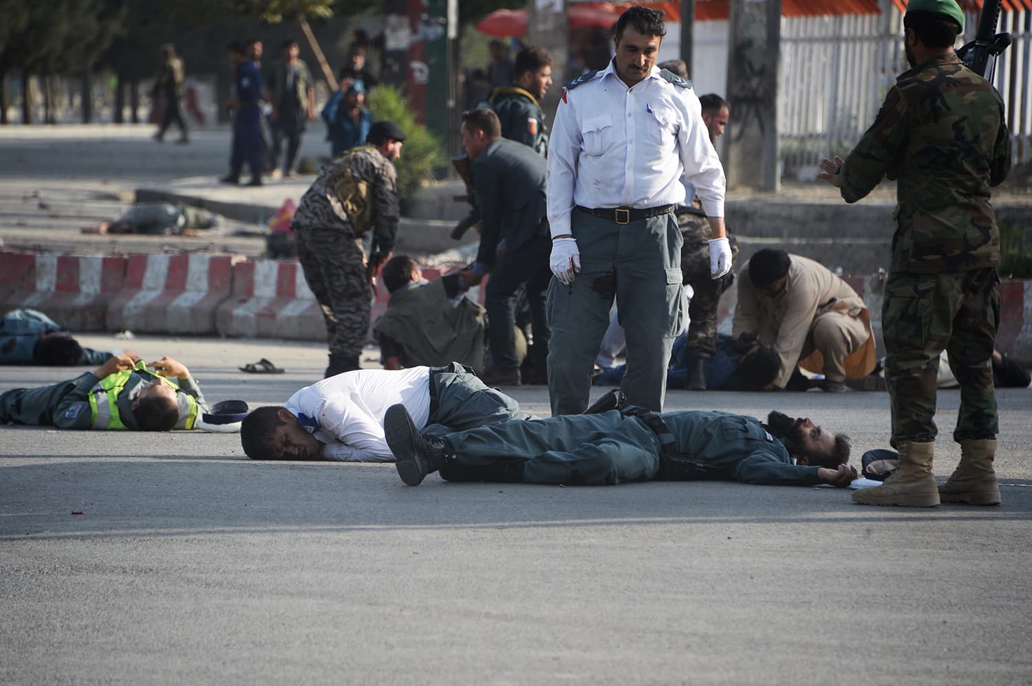 Afghan security forces stand near bodies of victims while others help injured people following a suicide attack in Kabul on July 22, 2018. —AFP