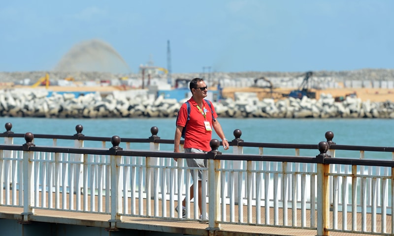 Colombo: A tourist walks past a site of a Chinese-funded $1.4 billion reclamation next to the main port. The land reclamation will add 269 hectare (672 acre) of new land to the capital of Colombo and officials say will attract $13 billion in direct investments to develop further infrastructure within the new facility.&mdash;AFP