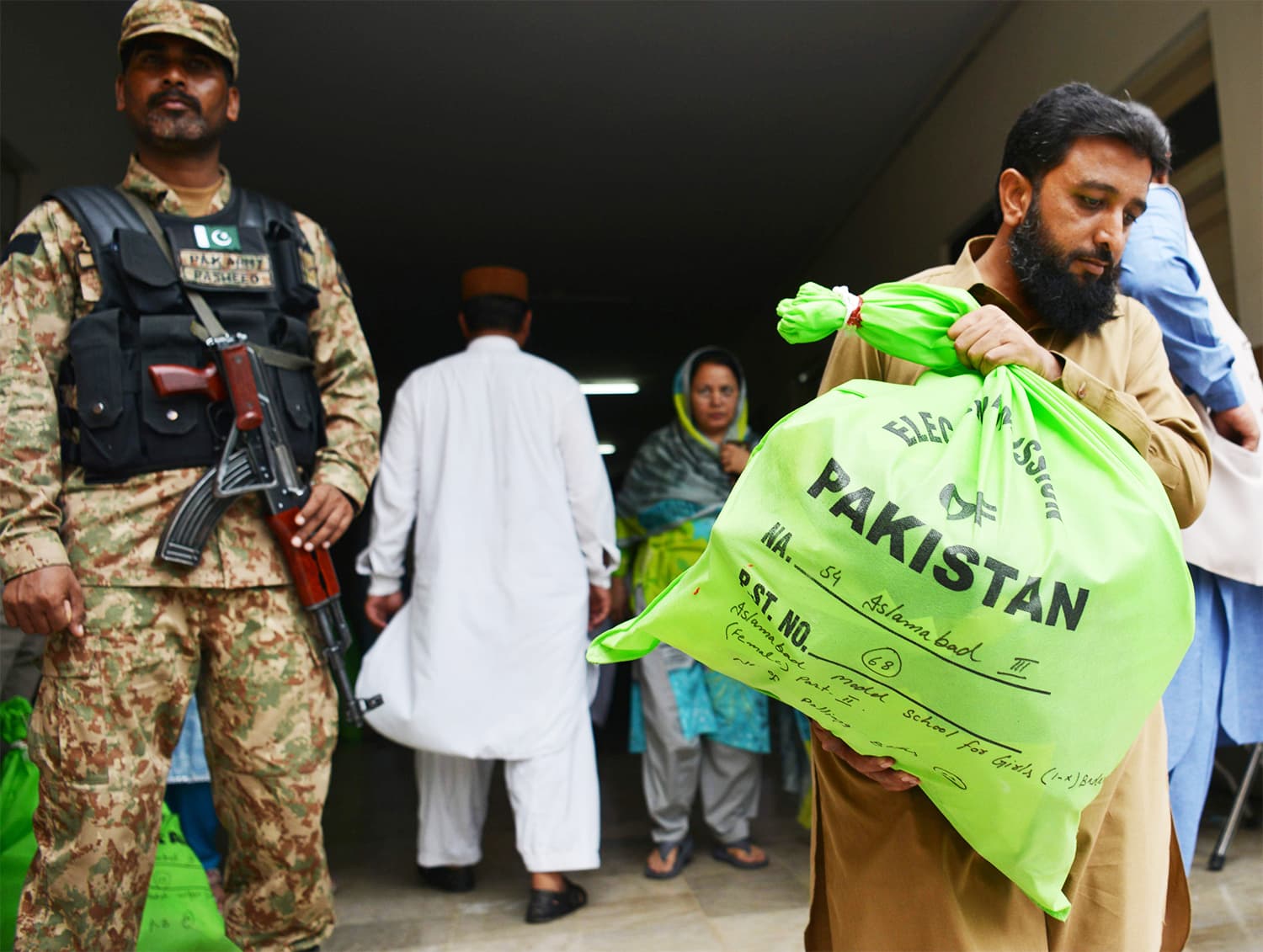 A soldier stands guard as an election official carries election materials at a distribution centre in Islamabad. ─AFP