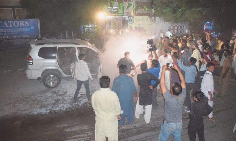 SMOKE billows from the car after it was hit by a cracker in Latifabad on Tuesday.—Dawn