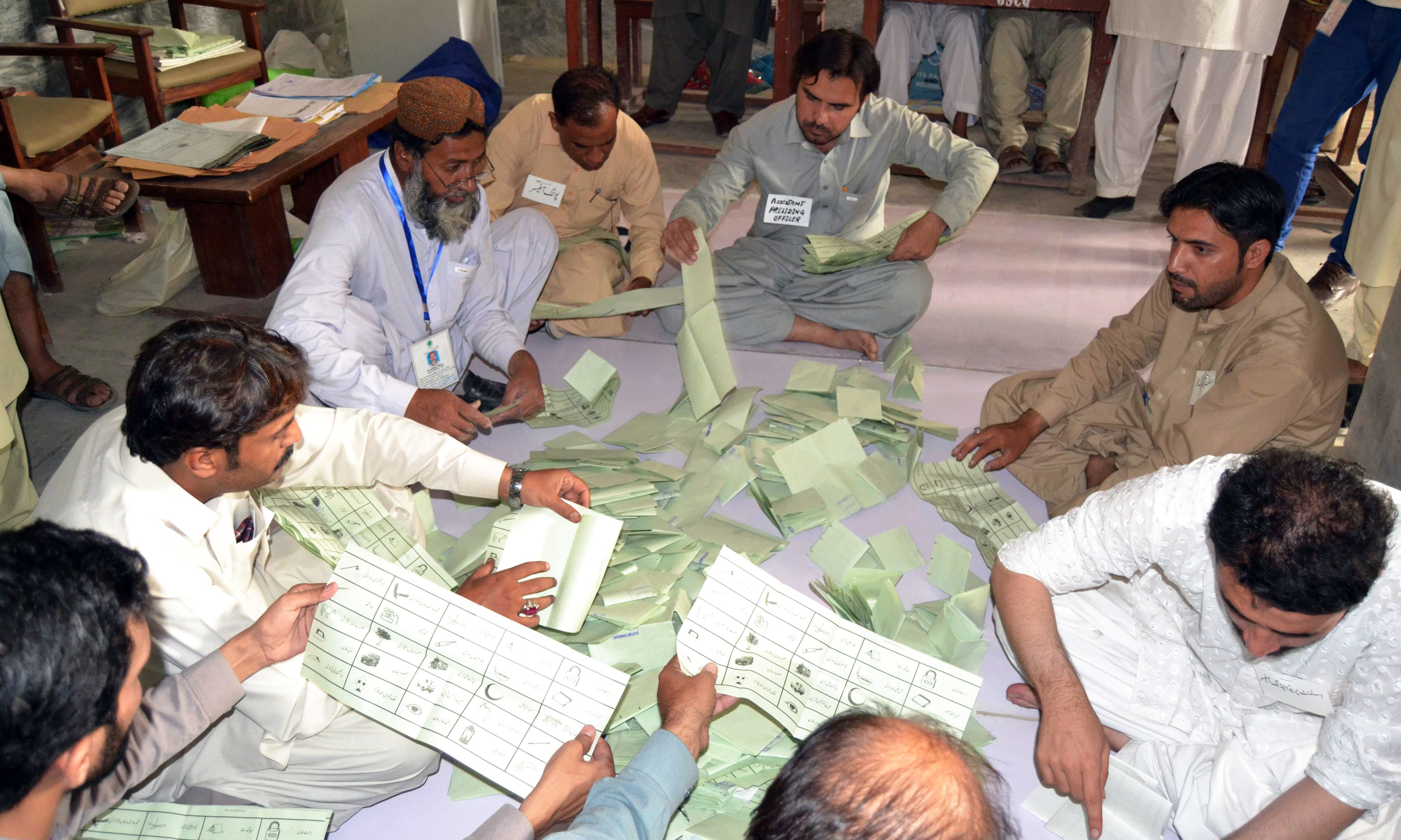 Election officials count ballots after polls closed at a polling station in Quetta. —AFP