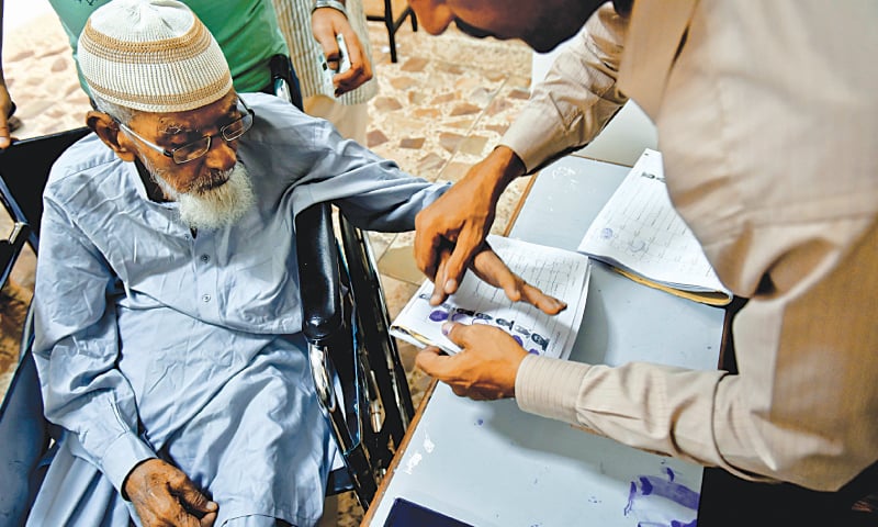 LAW enforcers frisk voters outside a polling station in Azizabad while (right) an elderly voter is helped to complete the formalities before casting his ballot in a Gulshan-i-Iqbal polling facility on Wednesday.—Fahim Siddiqi / White Star LAW enforcers frisk voters outside a polling station in Azizabad while (right) an elderly voter is helped to complete the formalities before casting his ballot in a Gulshan-i-Iqbal polling facility on Wednesday.—Fahim Siddiqi / White Star