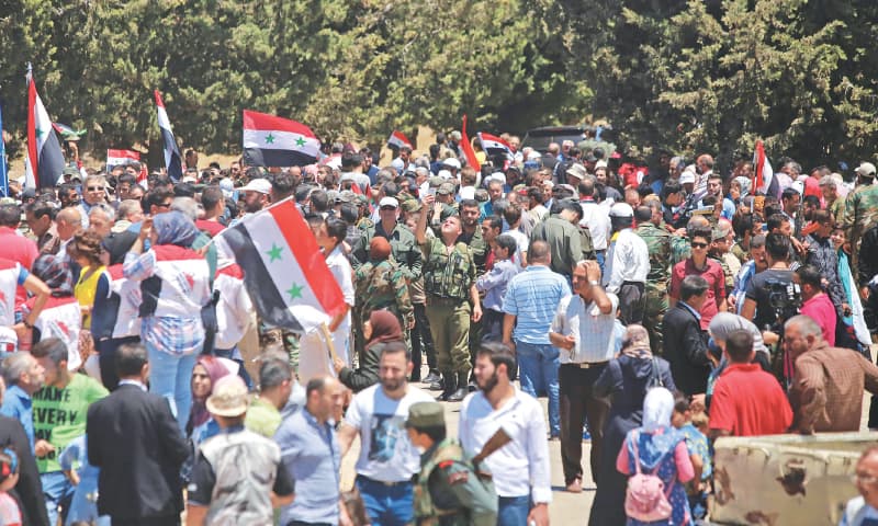 Syrians wave the national flag in the town of Quneitra in the Syrian Golan Heights on Friday.&mdash;AFP