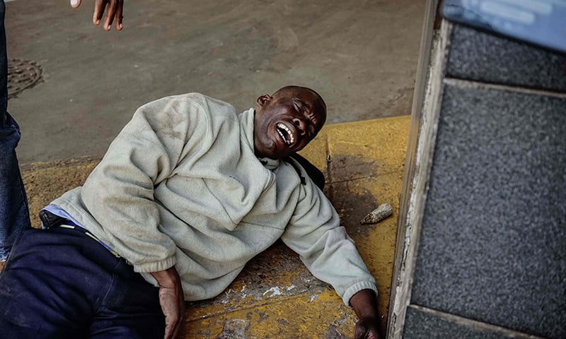 An injured man reacts as soldiers disperse demonstrators in Harare. — AFP