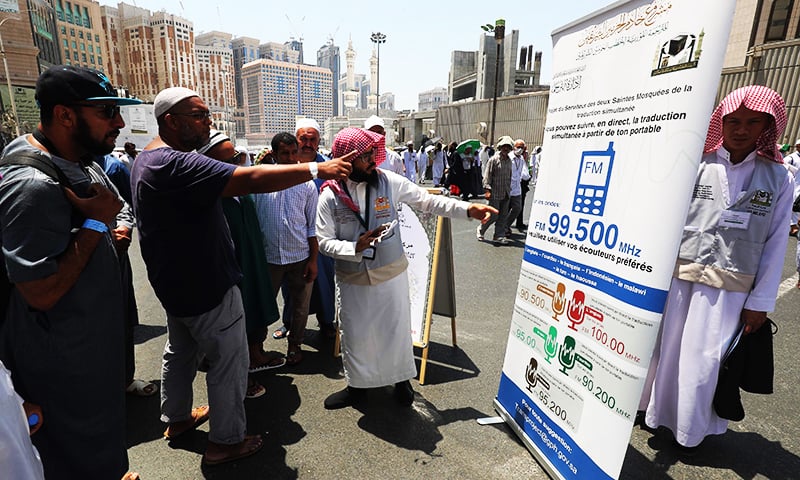 A translator helps pilgrims find information on a poster displaying helpful smartphone applications in the Saudi holy city of Makkah.&mdash;AFP