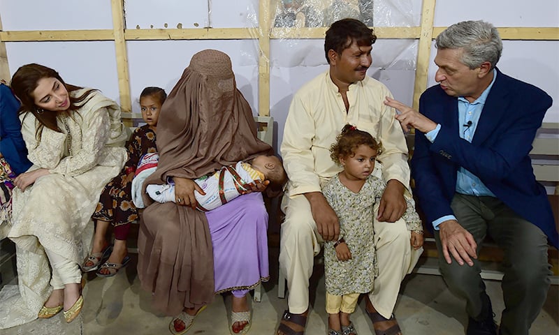 United Nations High Commissioner for Refugees Filippo Grandi (R) interacts with an Afghan refugee family at the Azakhel Voluntary Repatriation Centre as UNHCR advocate and actress Mahira Khan (L) looks on. ─ AFP