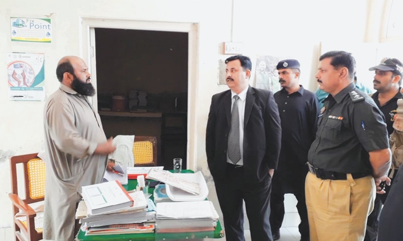 SENIOR judge along with police officials questions dispenser during a visit to government dispensary in Izzat ji Wandh village near Larkana on Thursday.&mdash;Dawn