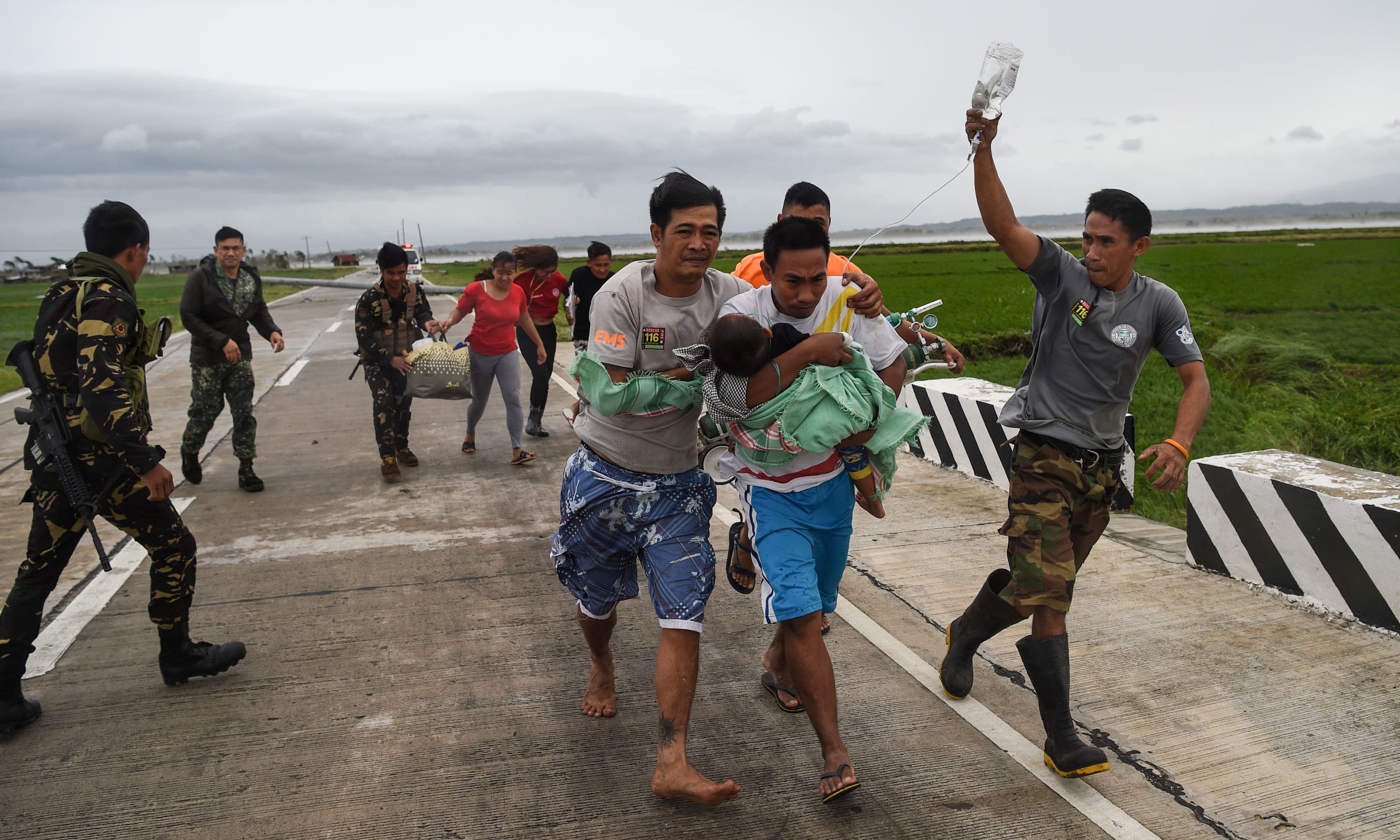 Philippine soldiers assist a family carrying their sick child to a waiting government vehicle after their ambulance failed to make it through a road blocked with fallen tree debris and electric posts toppled by strong winds from Super Typhoon Mangkhut in Baggao town, Cagayan province. — AFP