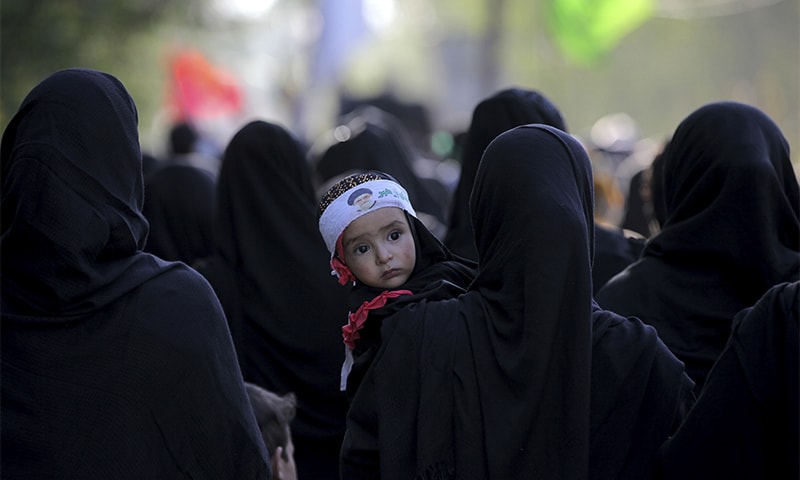 A Kashmiri Shia woman holds a child as she participates in a Muharram procession in Srinagar. ? AP