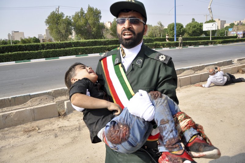 A Revolutionary Guard member carries a wounded boy after a shooting during a military parade marking the 38th anniversary of Iraq’s 1980 invasion of Iran on Saturday. — AP