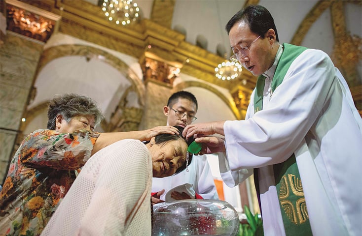 BEIJING: A priest baptises a woman after a mass at the  the state-run South Cathedral on Saturday.—AFP