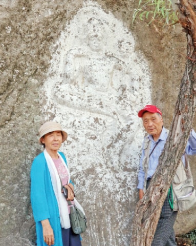 Dr So Gilsu with his wife at a rock-carved Buddha at Arab Khan Cheena, Swat. — Dawn