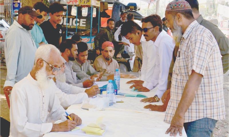 Voters seek information about their polling booths at a camp set up by a political party in NA-243 on Sunday. —Faysal Mujeeb/ White Star Voters seek information about their polling booths at a camp set up by a political party in NA-243 on Sunday. —Faysal Mujeeb/ White Star