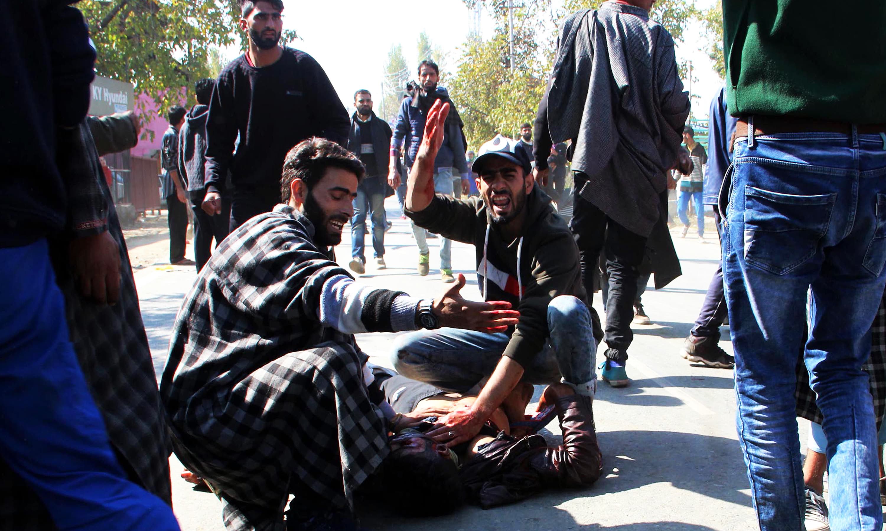 Kashmiri men gesture as another lies on the ground after a blast near a residential house where three suspected militants were killed during a gunfight with Indian forces in Kulgam. —AFP