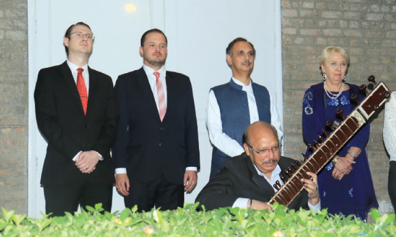 Ambassador Brigitta Blaha, Federal Minister Omar Ayub Khan  and embassy staff members with a musician playing the national anthems of Austria and Pakistan.