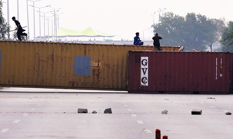 Supporters of the TLP sit on containers set up to block a street. &mdash; AFP