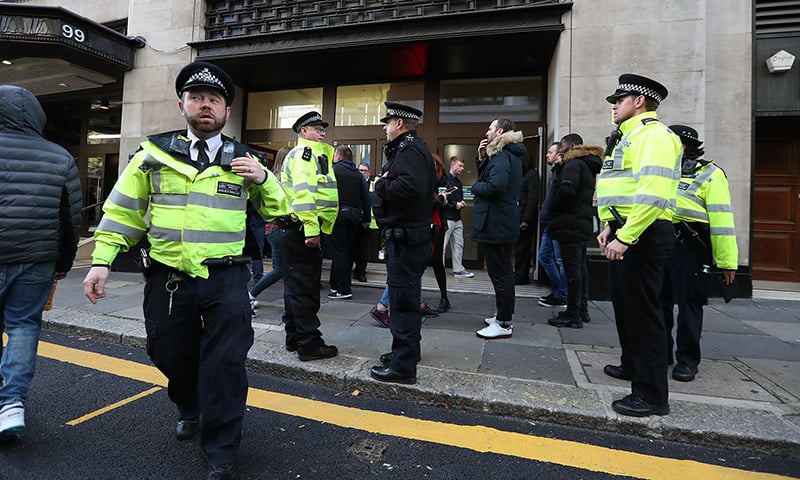 Police officers are seen outside the office building housing Sony Music's offices in London. —AFP