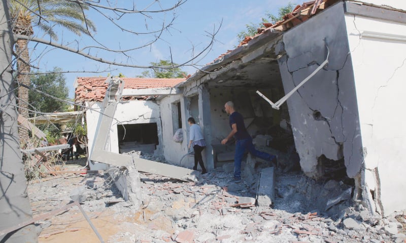 Ashkelon (Israel): Israelis inspect the damage to a house (left) caused by rockets fired from the Gaza Strip on Tuesday. Palestinians survey a destroyed residential building hit by Israeli air strikes in Gaza City.&mdash;Agencies