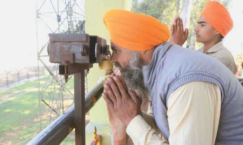 An Indian Sikh devotee offers prayers at Dera Baba Nanak, Gurdaspur, while looking through binoculars towards the Kartarpur Gurdwara. ─ AFP