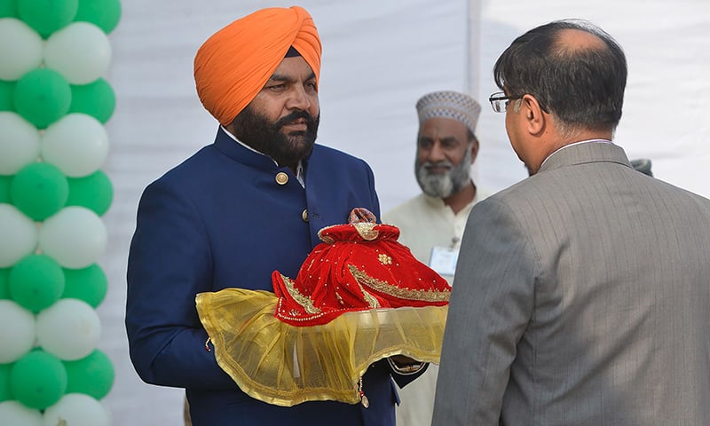 Indian Member of Parliament Gurjeet Singh Aujla (C) holds a pot containing water from the Sikh Golden Temple in Amritsar as he takes part in a groundbreaking ceremony for the Kartarpur corridor. ─ AFP