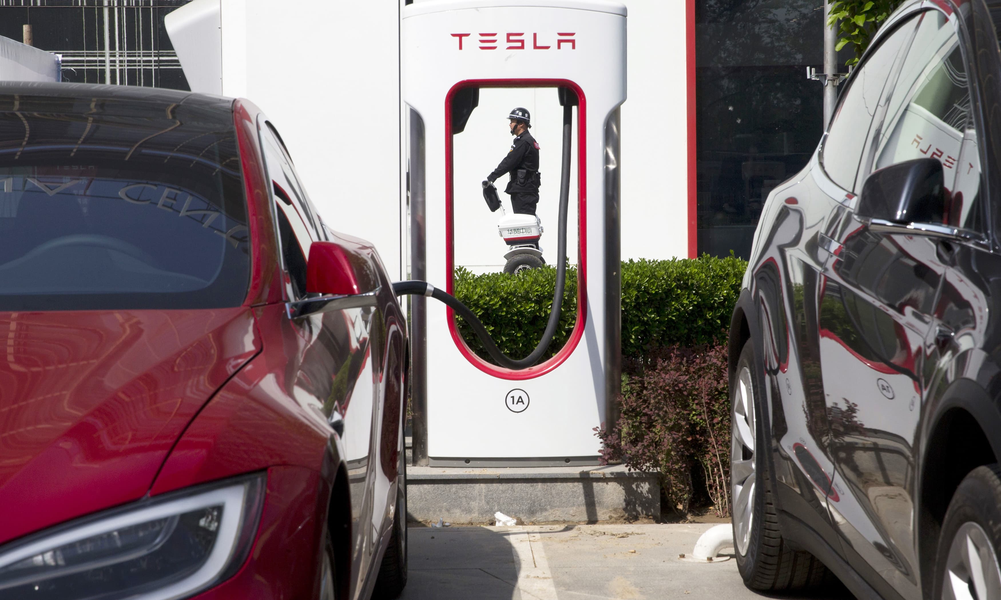 A security guard moves past Tesla electric vehicle charging station in Beijing. —AP/File