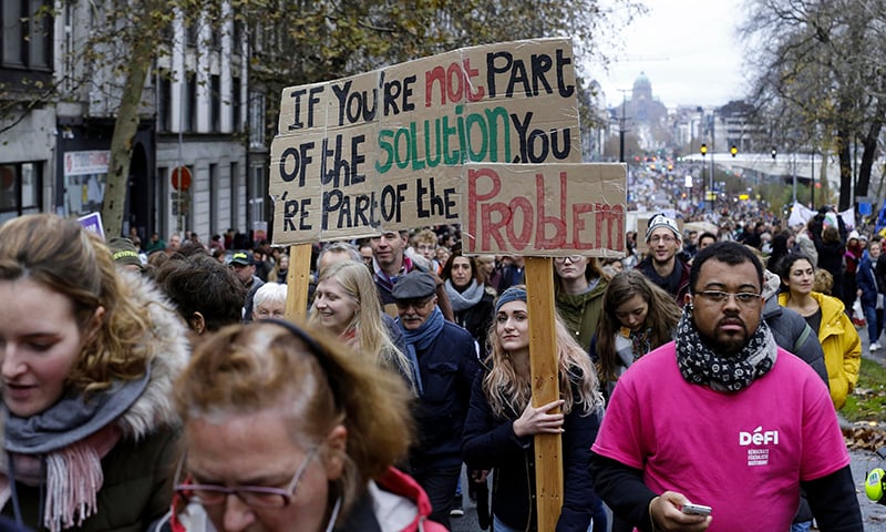 People hold a sign reading "If you're not part of the solution you're part of the problem" during the "Claim the Climate" march to raise awareness for climate change, in Brussels. — AFP People hold a sign reading "If you're not part of the solution you're part of the problem" during the "Claim the Climate" march to raise awareness for climate change, in Brussels. — AFP