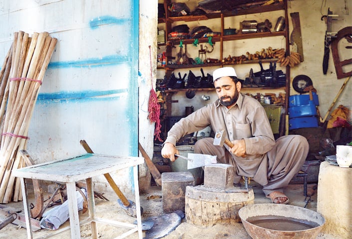 A blacksmith works at his outlet in a Swabi village. &mdash; Dawn