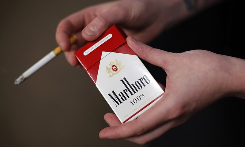 In this July 17, 2015, file photo, store manager Stephanie Hunt poses for photos with a pack of Marlboro cigarettes, an Altria brand, at a Smoker Friendly shop in Pittsburgh.  &mdash; AP