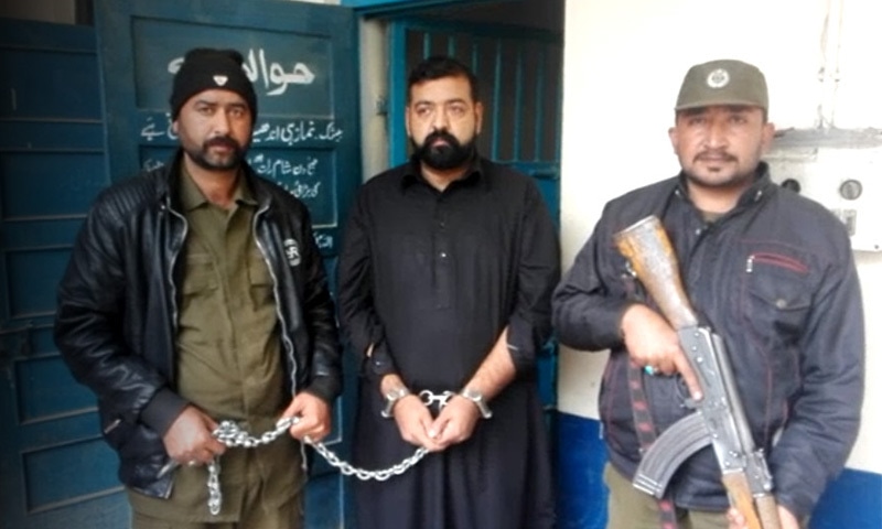 مبینہ منشیات اسمگلر پولیس اہلکاروں کی تحویل میں &mdash;فوٹو:ڈان نیوز