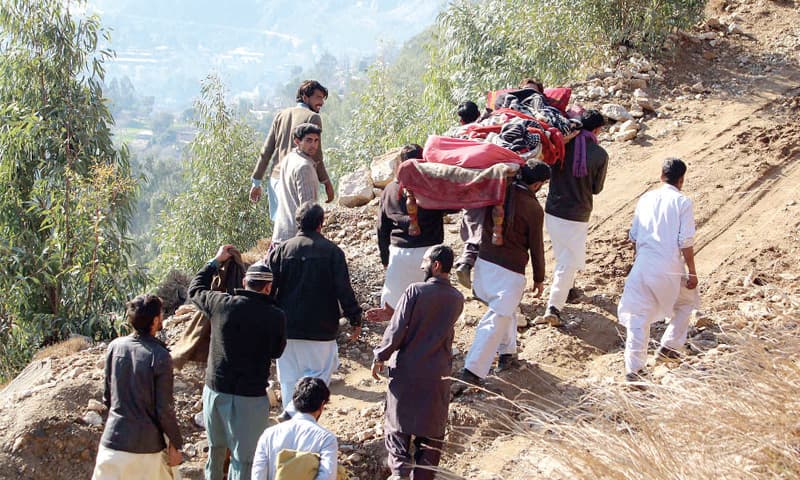 People carry a patient on a charpoy in mountainous Khataksar area after blockade of roads due to landslides. &mdash; Photo by Umar Bacha