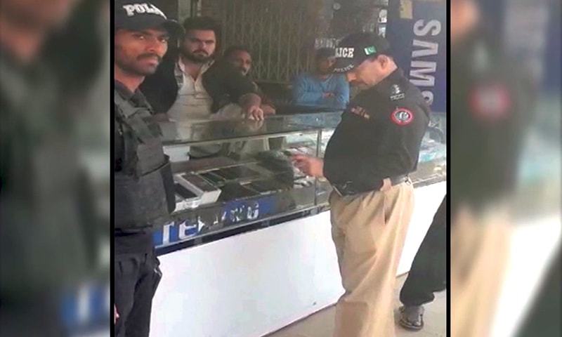 A police official is seen at a mobile phone shop inside the . — DawnNewsTV A police official is seen at a mobile phone shop inside the . — DawnNewsTV