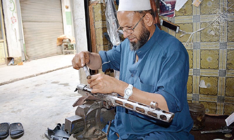 Artisans engrave patterns on weapons at a workshop in Dara Adamkhel arms market. &mdash; Dawn