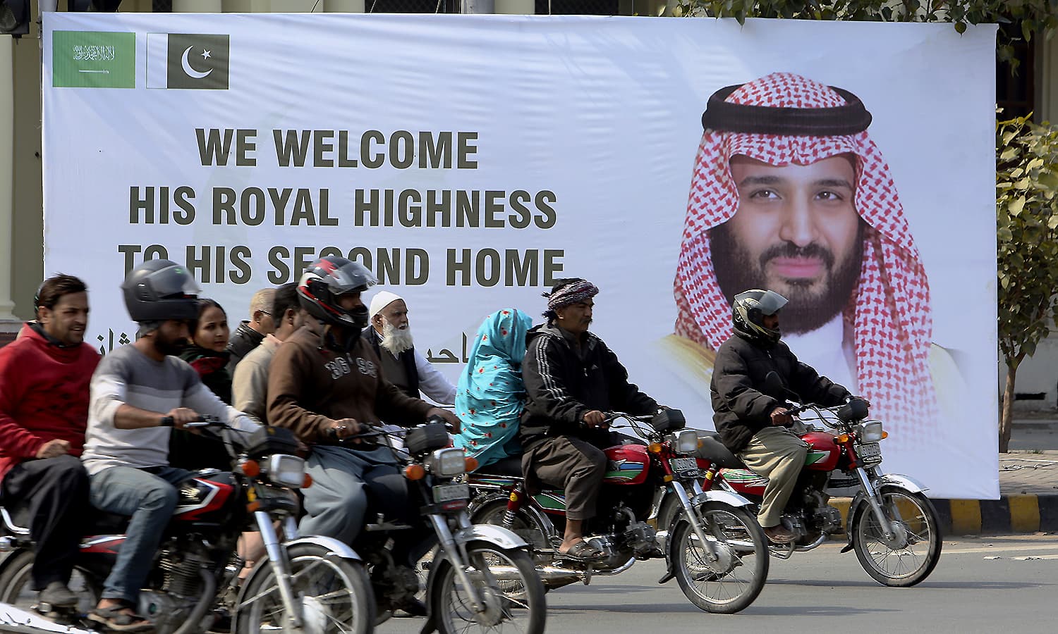 Motorcyclists pass by a banner welcoming Saudi Arabia's Crown Prince Mohammed bin Salman displayed on the occasion of his visit, in Lahore. ─ AP