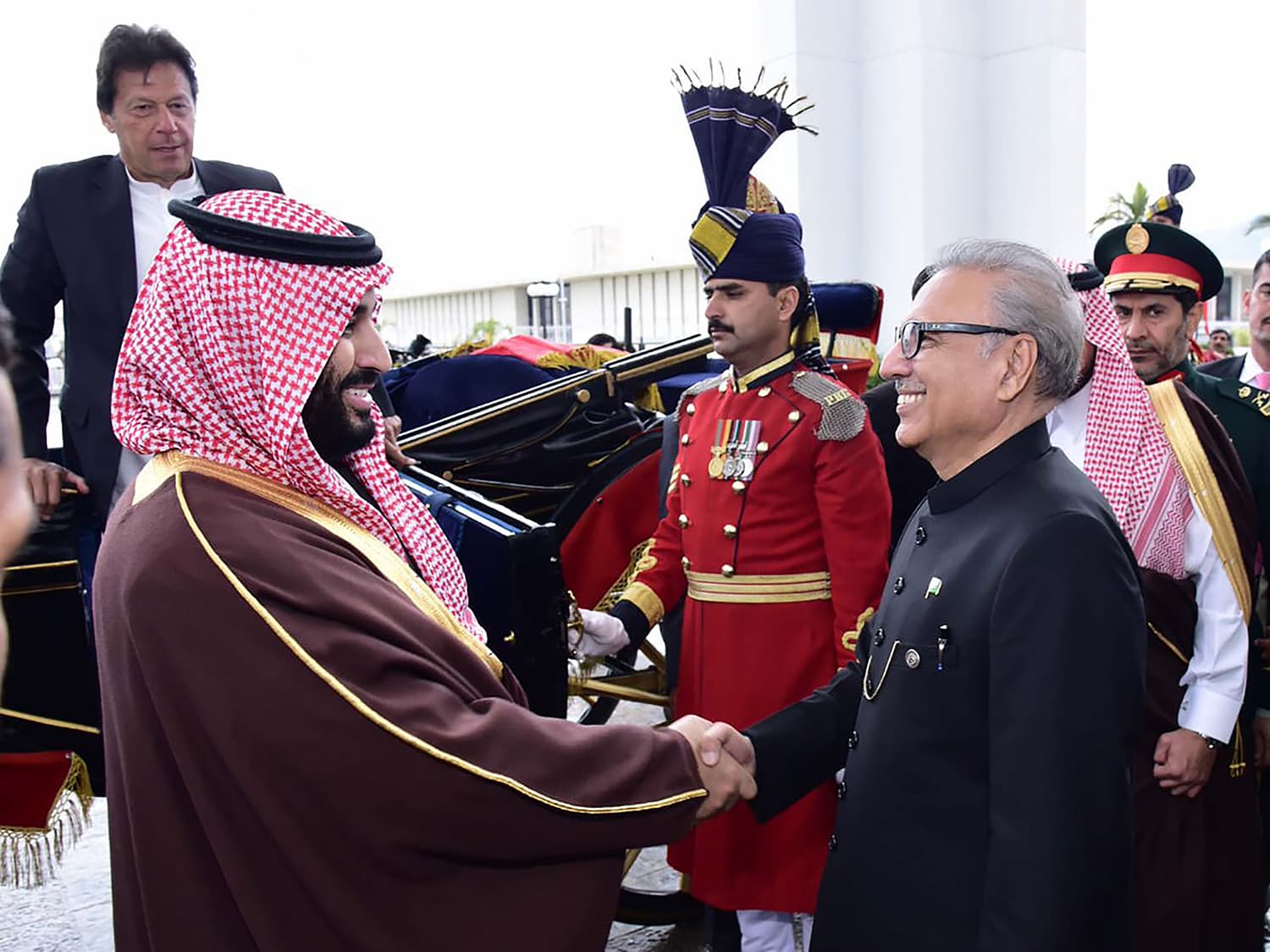 President Alvi shakes hands with the crown prince as Prime Minister Imran Khan looks on. — AFP