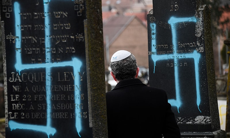 A man walks by graves vandalised with swastikas at the Jewish cemetery in Quatzenheim, on February 19, 2019, on the day of a nationwide marches against a rise in anti-Semitic attacks.  — AFP