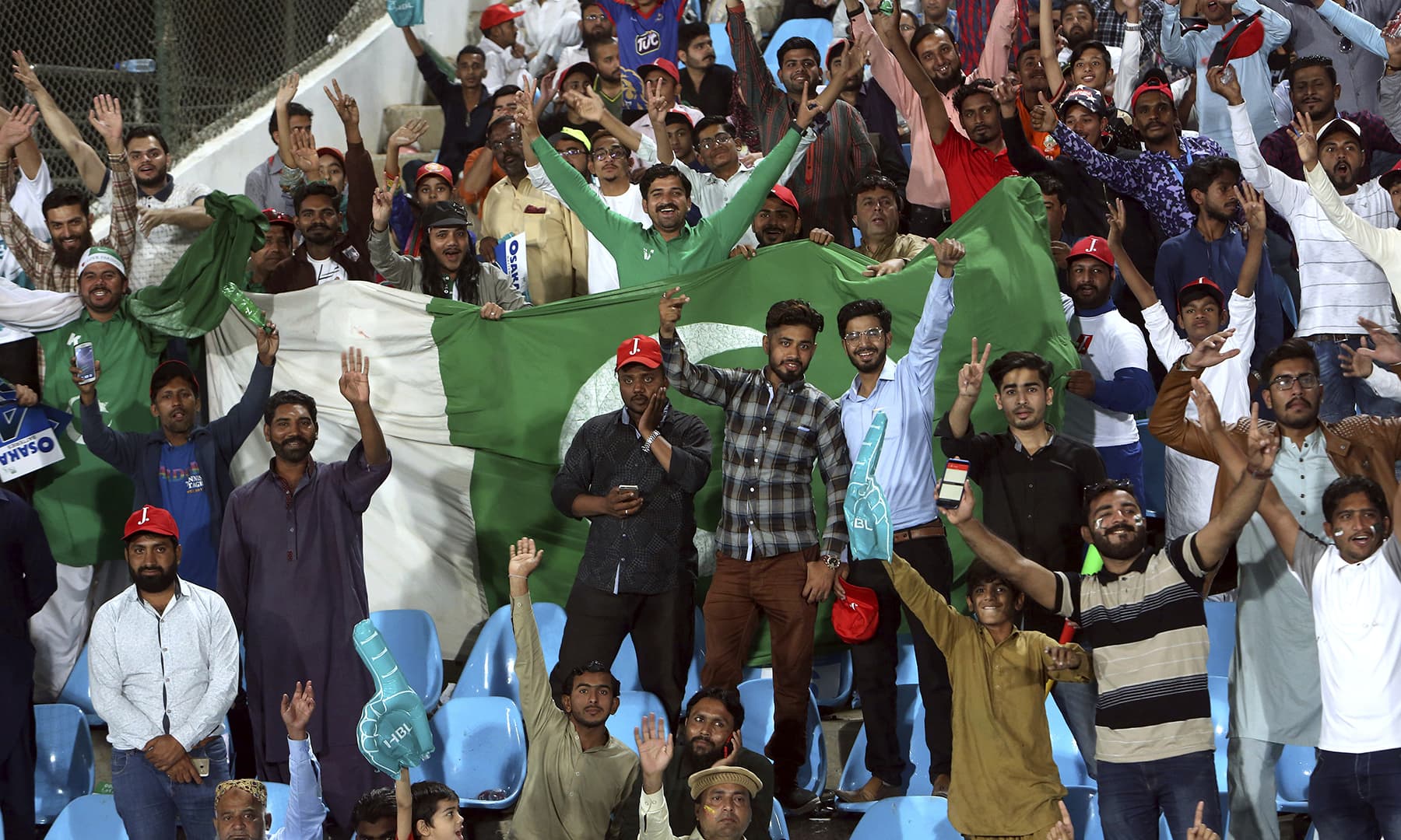 Spectators cheering and waving the Pakistan flag proudly. — AP