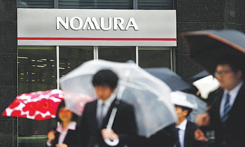 People walk past a branch of the Nomura financial services group in Tokyo.—Reuters People walk past a branch of the Nomura financial services group in Tokyo.—Reuters