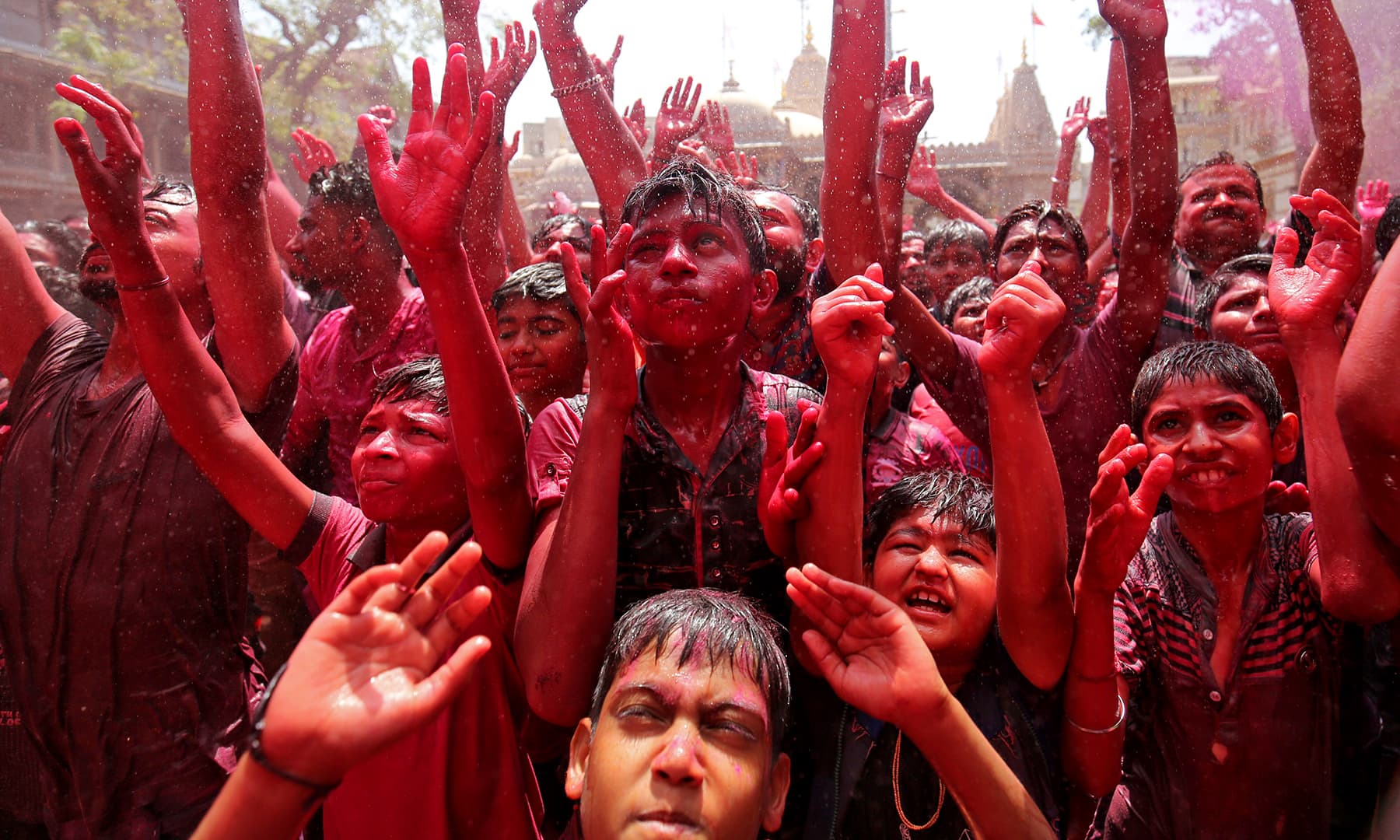 Hindu devotees raise their hands daubed in colours as they pray on a temple premises during Holi celebrations in Ahmedabad, India. &mdash; Reuters