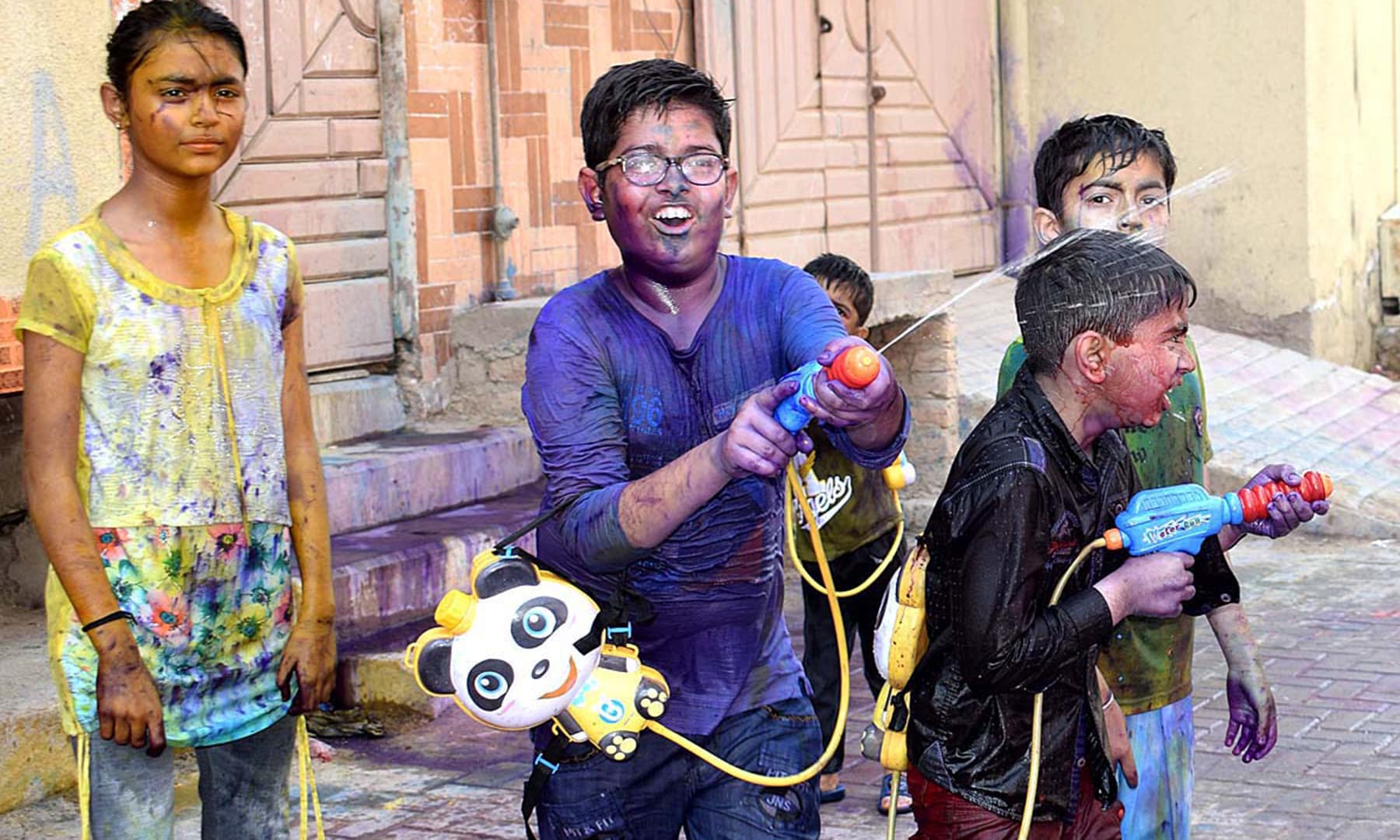 A group of children make use of water guns to shoot coloured water at one another as they celebrate Holi in Larkana, Pakistan, on March 20, 2019. &mdash; APP
